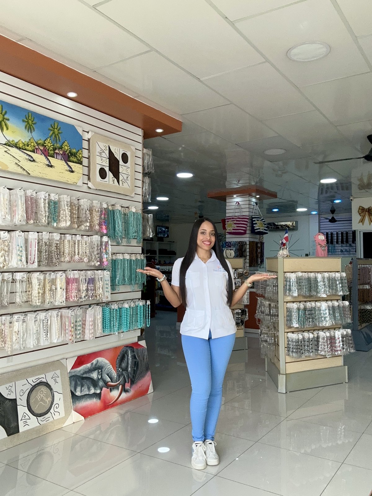 Miembro del equipo de Rijo Suplidora dando la bienvenida en el showroom, rodeada de joyería y artesanías exhibidas